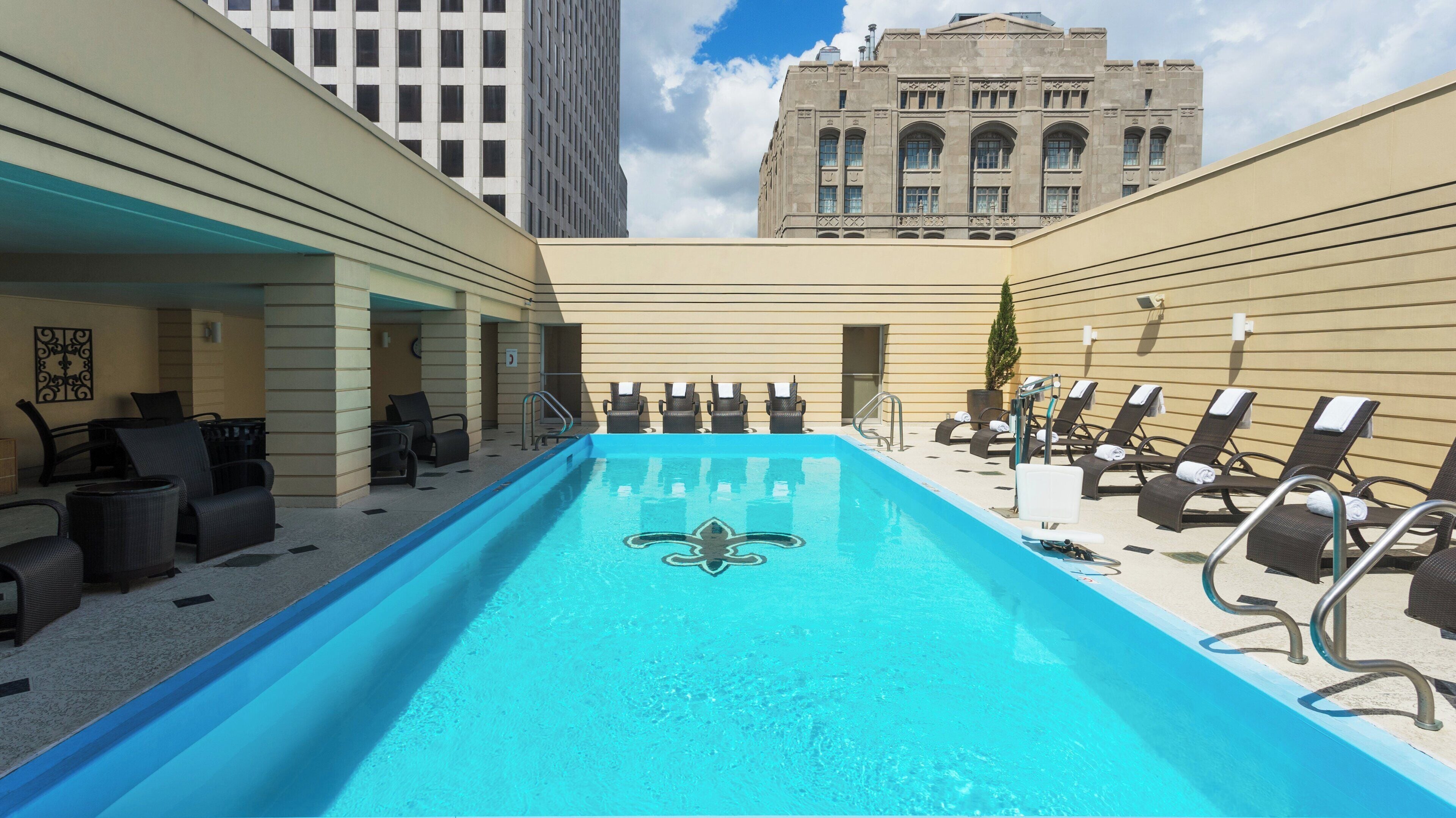 A rooftop pool with lounge chairs and a view of a historic building.