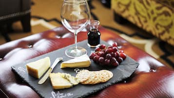 Una pizarra con queso, galletas, uvas y una copa de vino sobre una mesa de cuero.