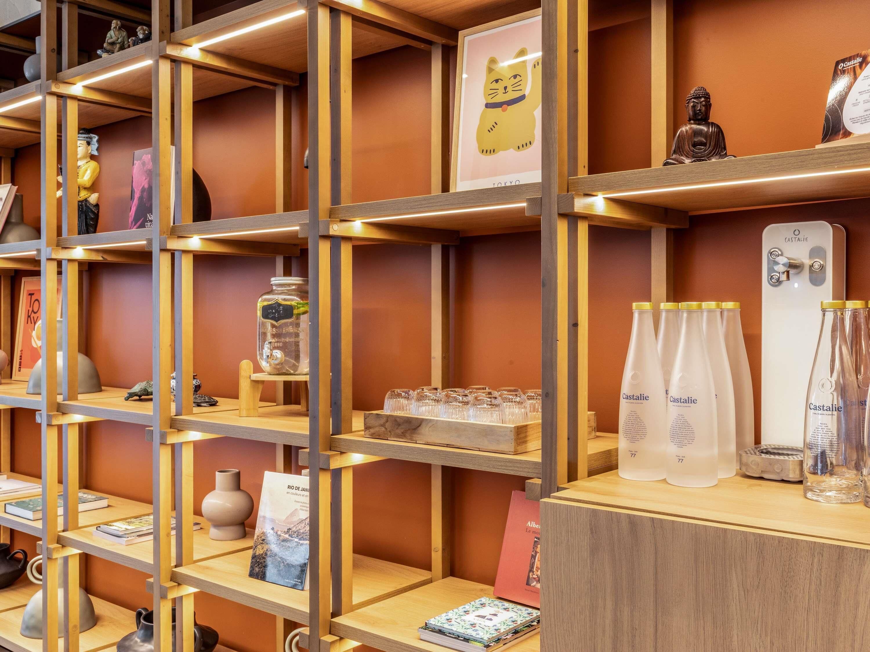 A well-organized shelf with various items including books, decorative objects, and bottles of Castalie.