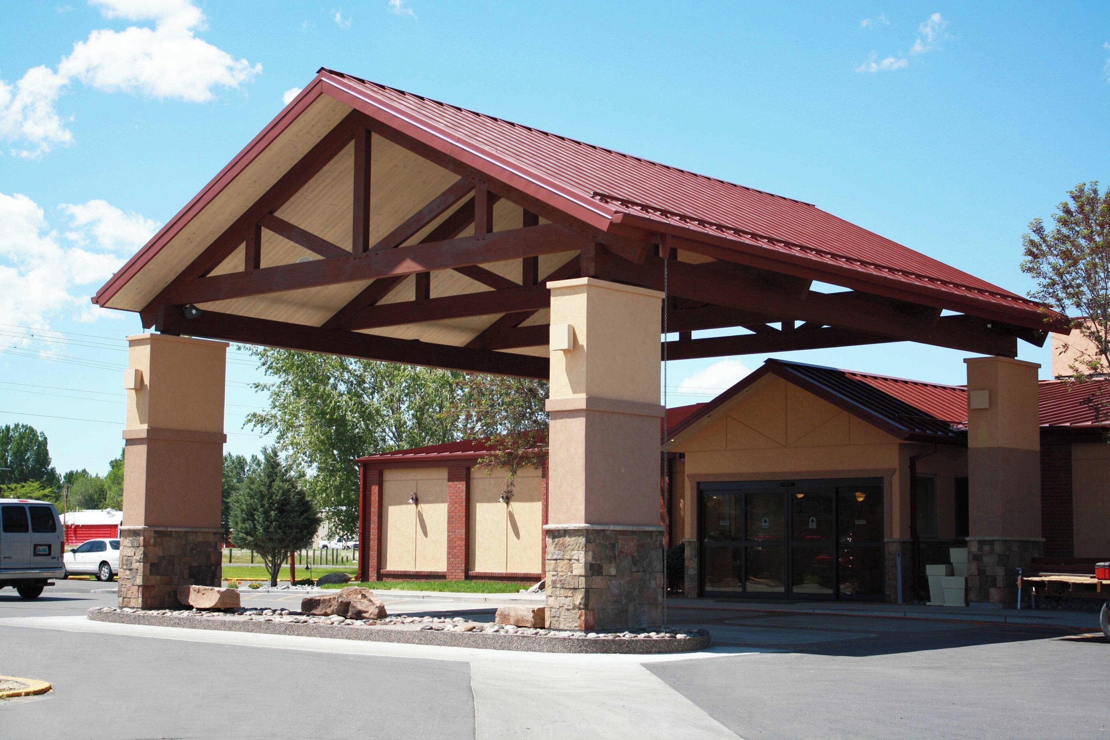 A building with a covered entrance, stone pillars, and a red roof.