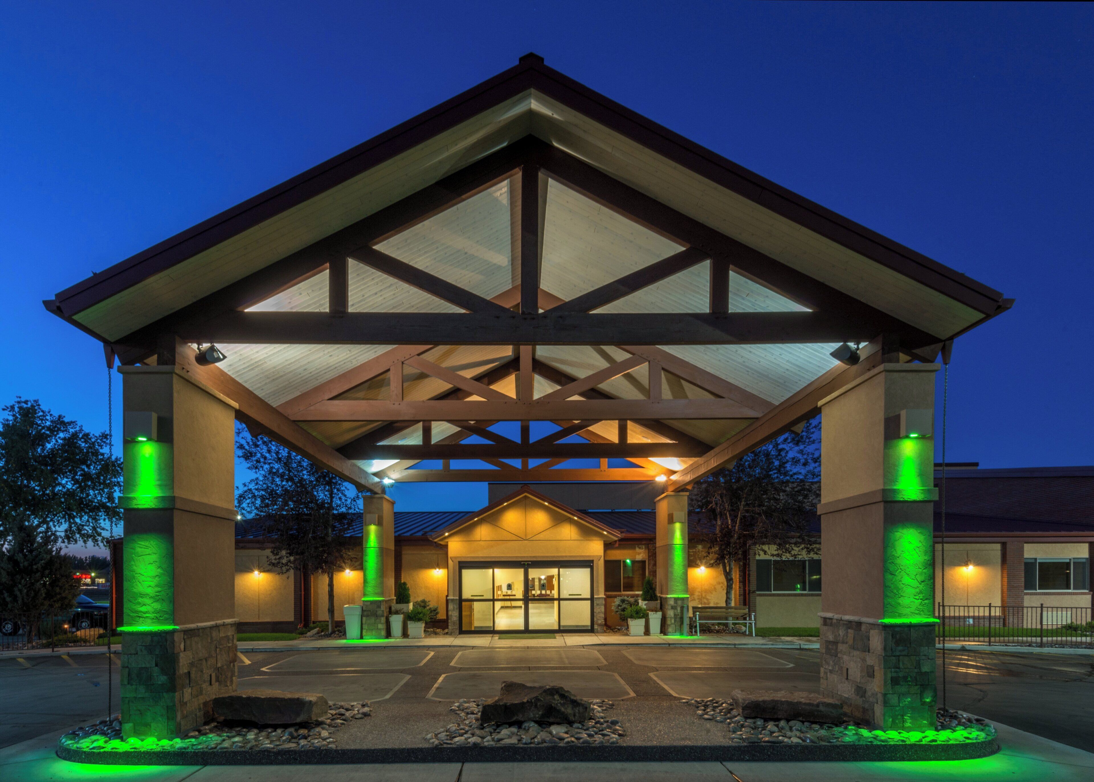 A building with a covered entrance, stone pillars, and a parking lot.