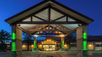 A building with a covered entrance, stone pillars, and a parking lot.