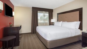 A hotel room with a large bed, a desk, a television, and a window with curtains. - Holiday Inn Riverton by IHG (Riverton)