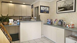 A kitchen with white cabinets, a countertop with various items, and a framed picture on the wall. - San Francisco Inn (San Francisco)