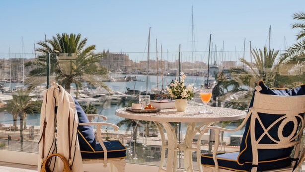 A balcony with a table and chairs overlooking a marina with boats. - Hotel Victoria Gran Meliá (Palma de Mallorca)