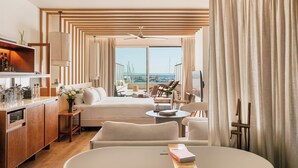 A modern hotel room with a balcony, a dining area, and a view of the marina. - Hotel Victoria Gran Meliá (Palma de Mallorca)