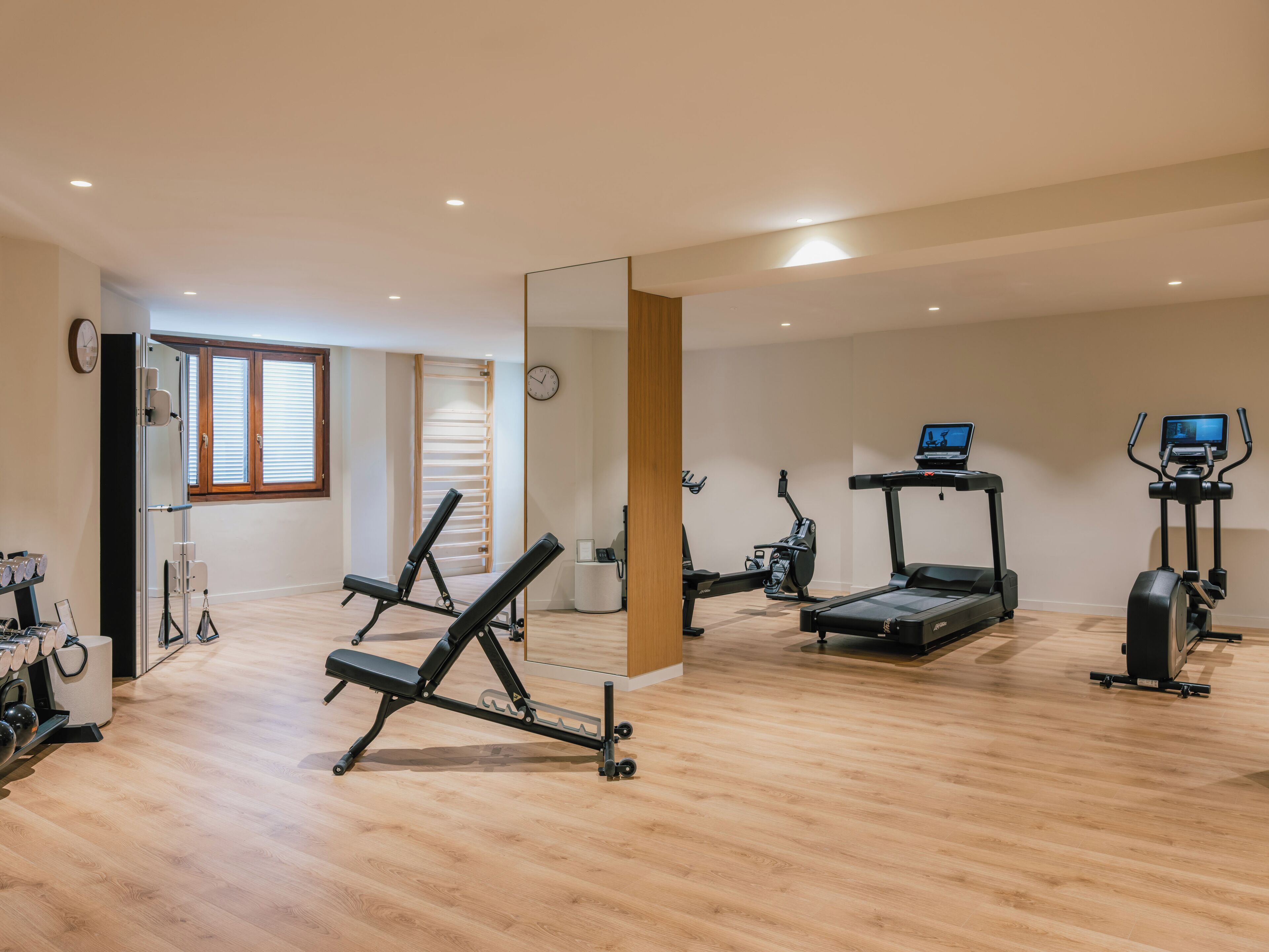 Un gimnasio con equipo de ejercicio, un espejo y un reloj en la pared.