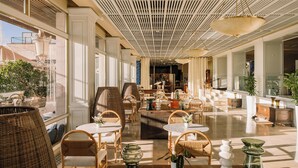 A spacious lobby with high ceilings, large windows, and a variety of seating arrangements including wicker chairs and tables. - Hotel Victoria Gran Meliá (Palma de Mallorca)