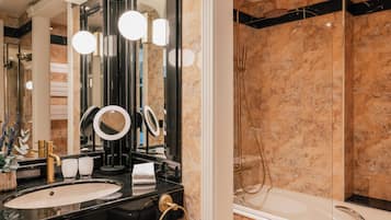 Une salle de bain moderne avec un lavabo noir, des accessoires dorés et un grand miroir.