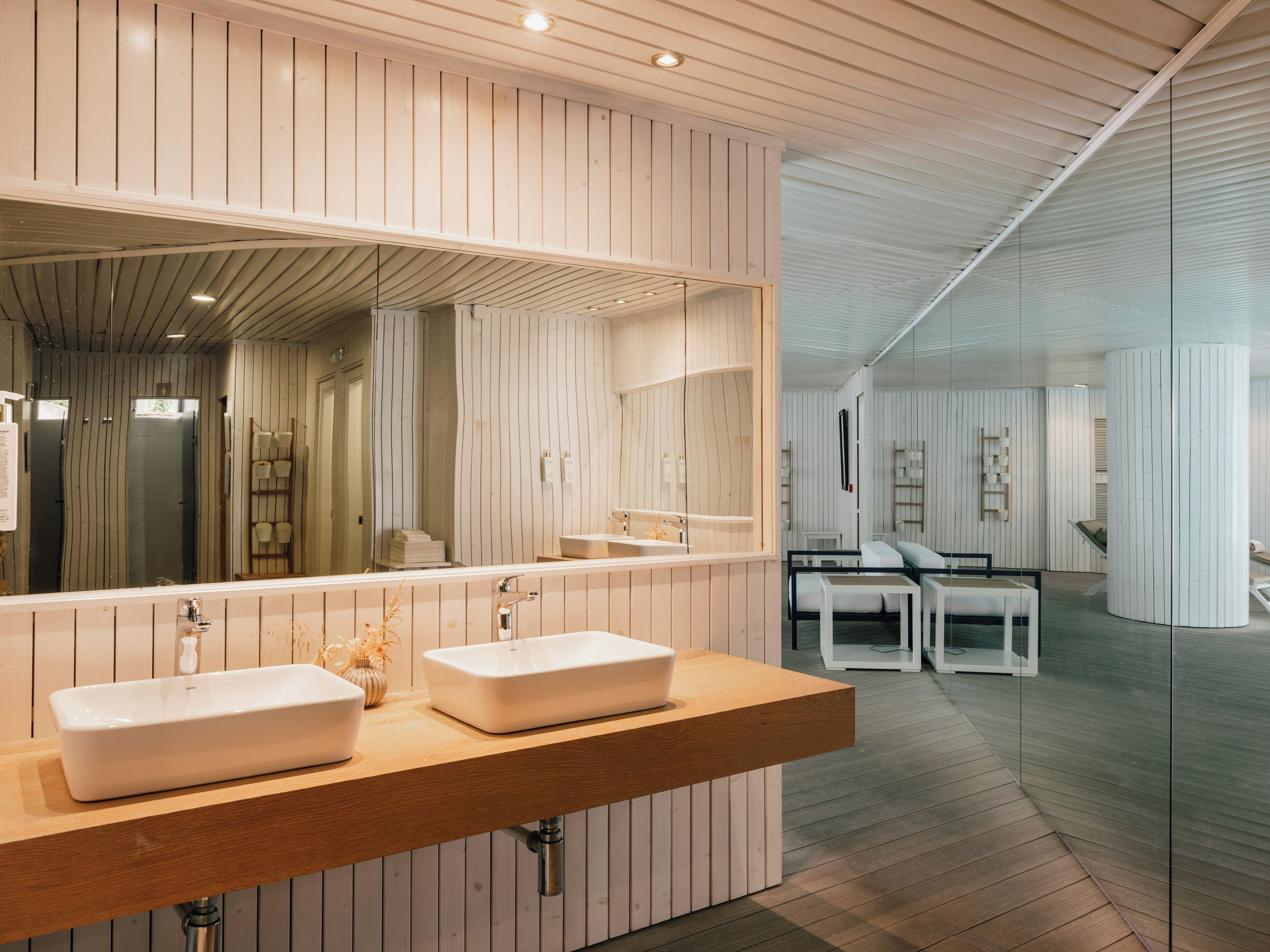 A modern bathroom with two sinks, a large mirror, and wooden paneling.