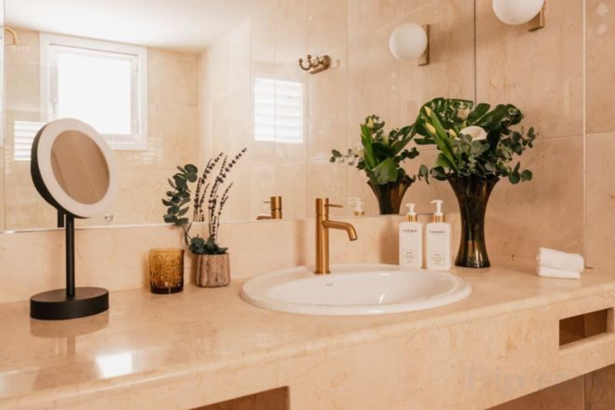 Een badkamer met een ronde spiegel, een wastafel en een vaas met bloemen.