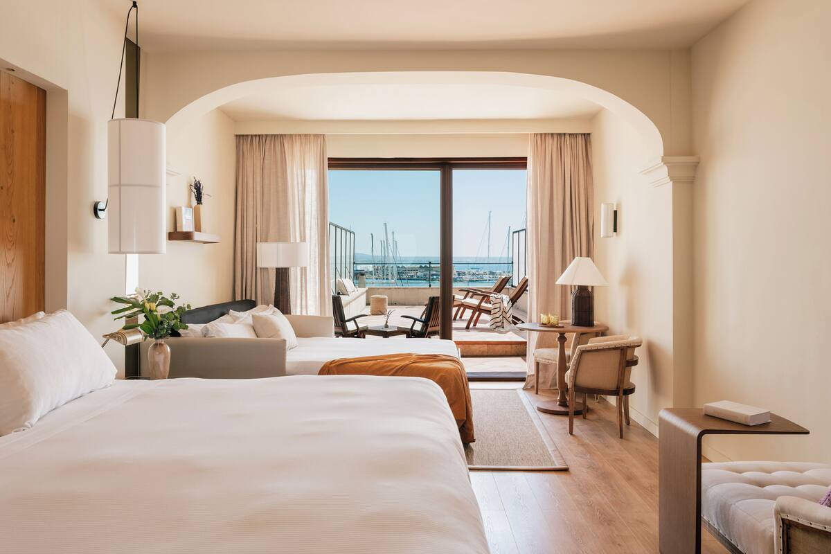 Habitación de hotel con una cama grande, un escritorio, una silla y vistas al mar.