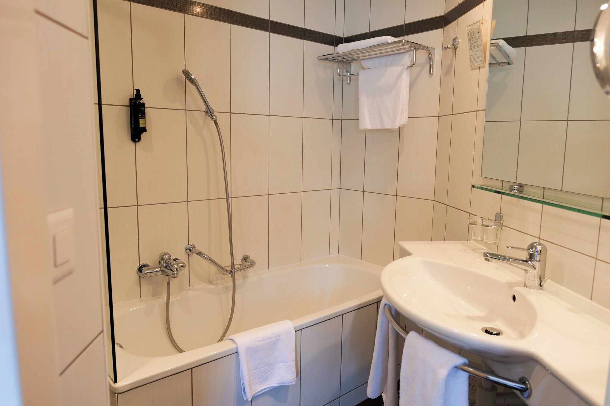 A modern bathroom with a bathtub, a sink, and a glass shelf.