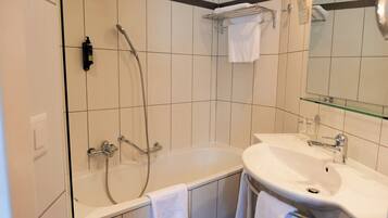 A modern bathroom with a bathtub, a sink, and a glass shelf.