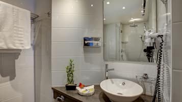 Un bagno moderno con uno specchio grande, un lavandino, un portasciuga, una piccola pianta e un telefono.
