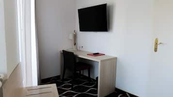 Una habitación pequeña con escritorio, silla y televisor de pantalla plana en la pared.