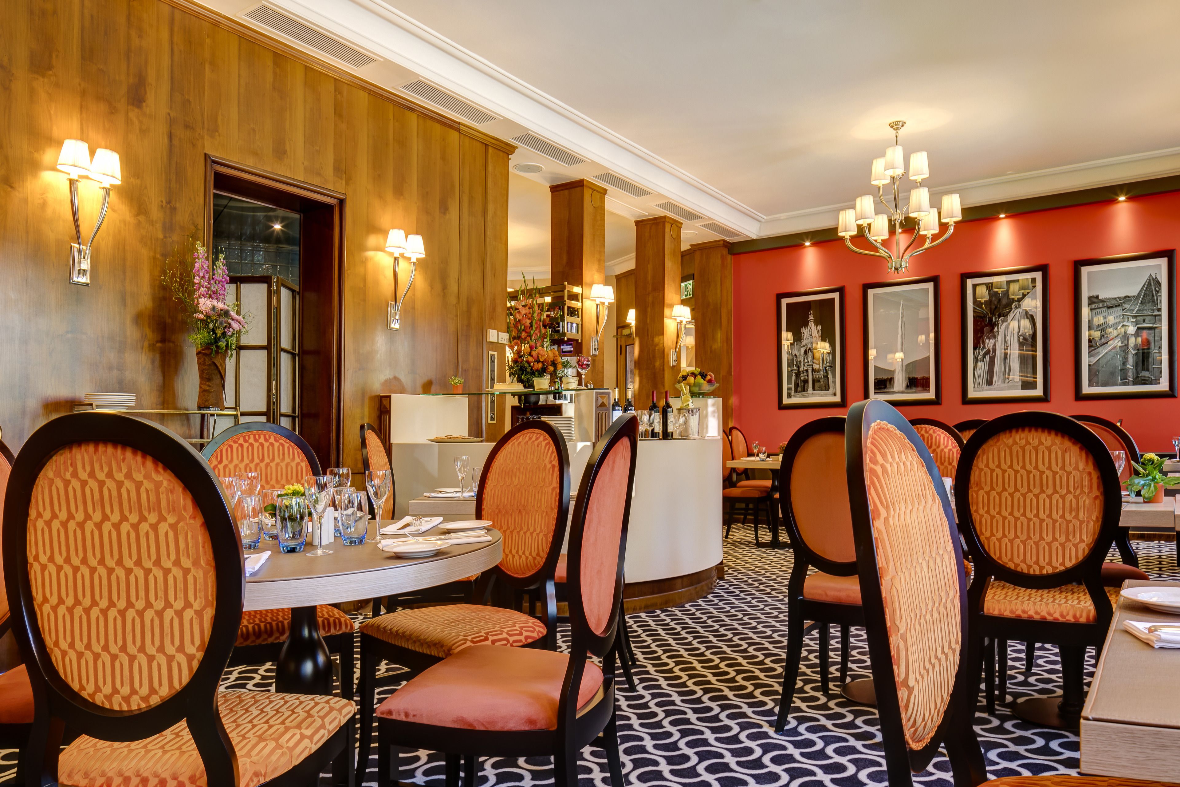 Ein Restaurant mit runden Tischen, gepolsterten Stühlen und einem gemusterten Boden.