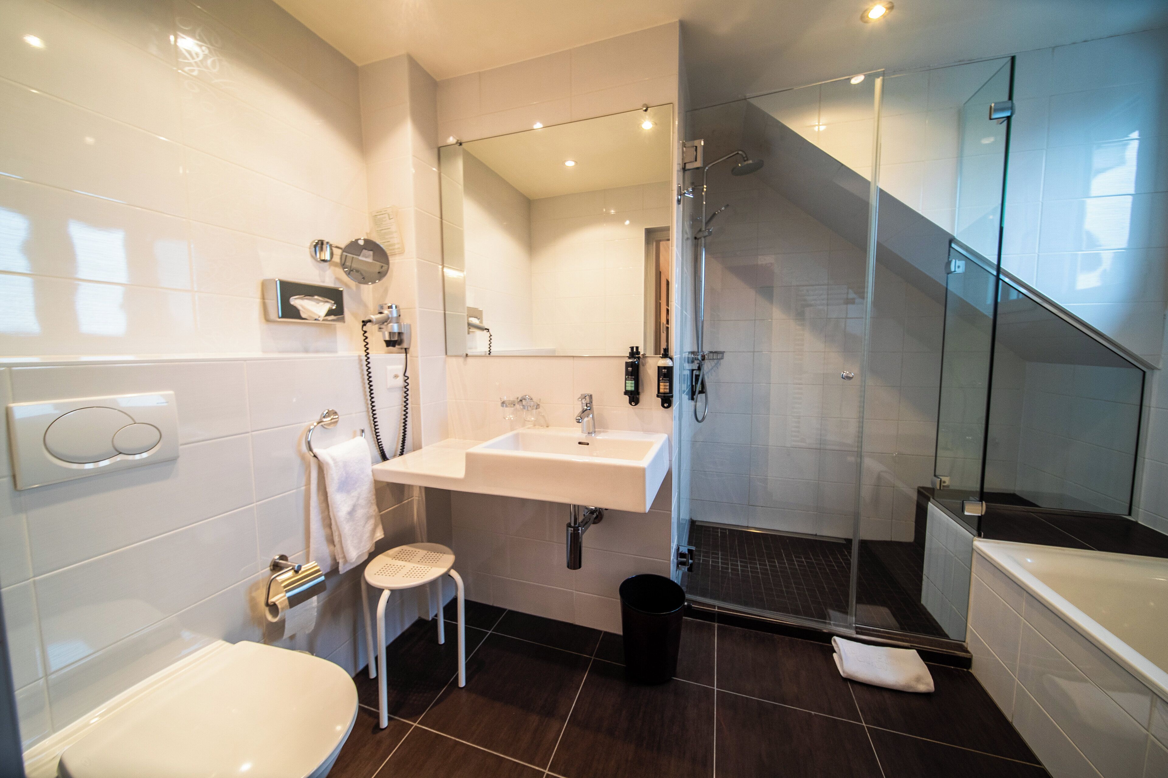 A modern bathroom with a toilet, sink, mirror, shower, and bathtub.