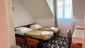 Quarto de hotel com duas camas, uma mesa pequena e uma cadeira.