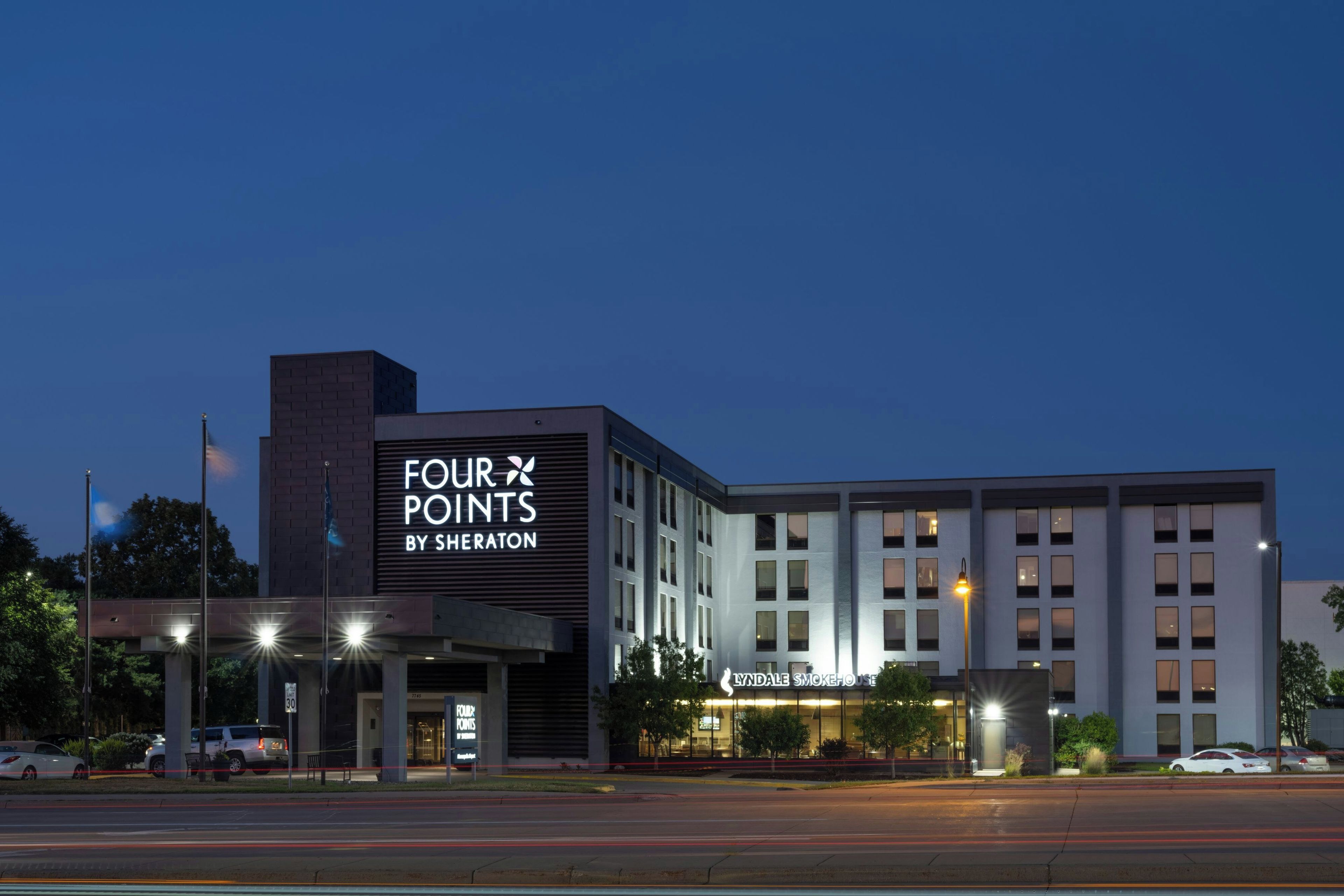 Un hotel con un llamativo letrero de 'Four Points by Sheraton', estilo arquitectónico moderno y una entrada visible.