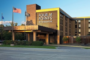 A hotel with a modern facade, a prominent sign reading 'FOUR POINTS BY SHERATON,' and a flagpole with an American flag. - Four Points by Sheraton Mall of America Minneapolis Airport (Richfield)
