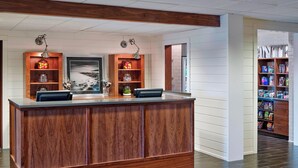 A reception desk with wooden paneling, two pendant lights, and shelves with various items. - Four Points by Sheraton Mall of America Minneapolis Airport (Richfield)