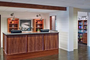 A reception desk with a wooden finish, a framed landscape painting, and a glass jar with candies. - Four Points by Sheraton Mall of America Minneapolis Airport (Richfield)