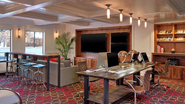 A modern conference room with a large table, multiple chairs, a sofa, and a bookshelf. - Four Points by Sheraton Mall of America Minneapolis Airport (Richfield)