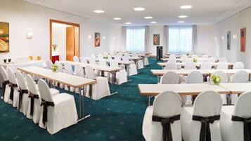 A conference room with rows of tables and chairs, a podium, and artwork on the walls.