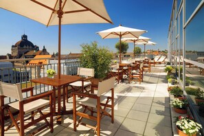 A rooftop terrace with wooden tables and chairs, large umbrellas, and potted plants. - Sheraton Carlton Hotel Nuernberg (Nuremberg)