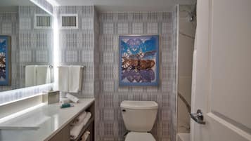 Une salle de bain comprenant des toilettes, un lavabo, un miroir et une douche.