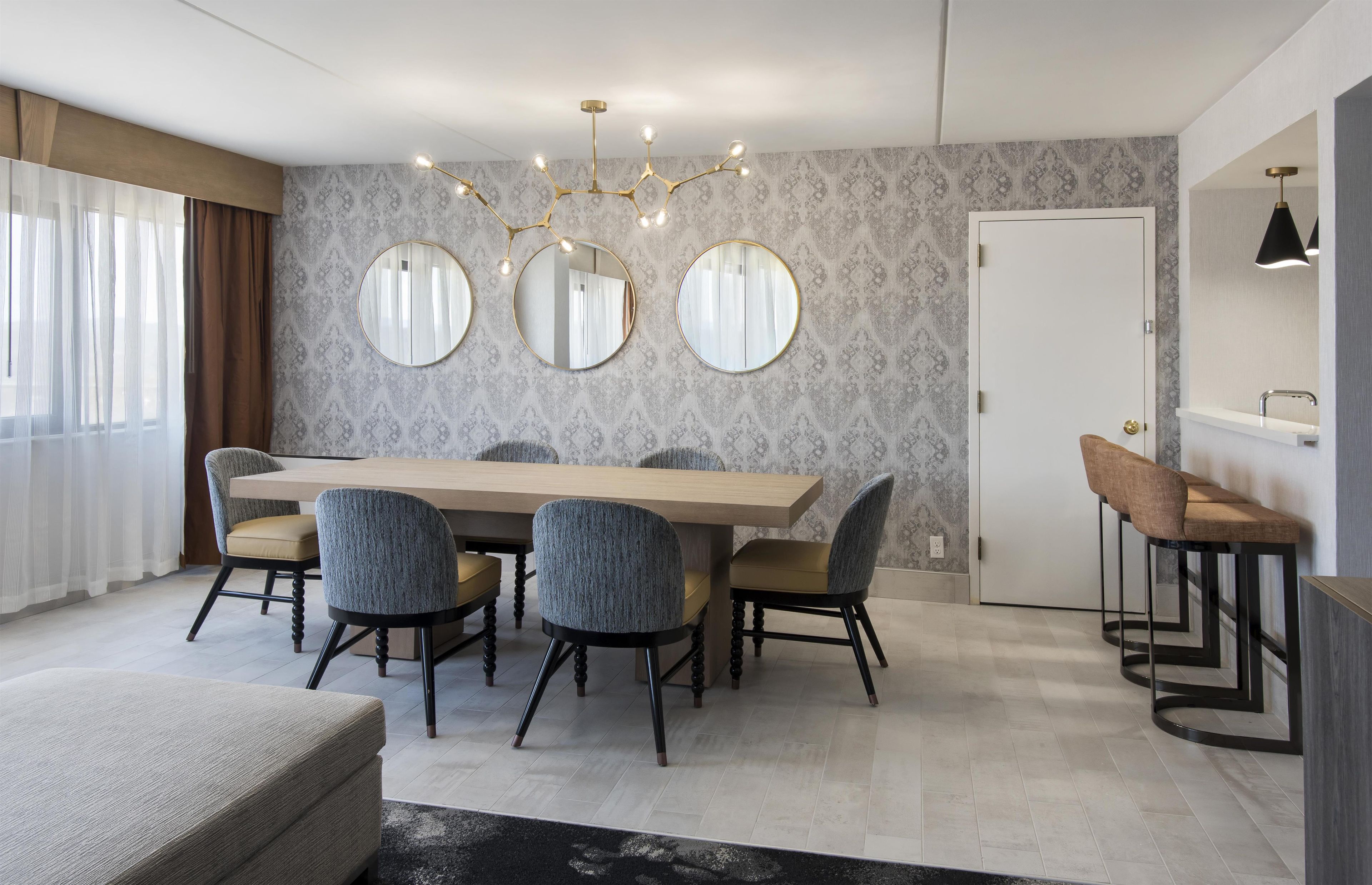 Un espace de salle à manger moderne avec une table en bois, quatre chaises et un lustre.