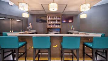 Un espace bar avec un comptoir, des tabourets de bar de couleur turquoise et des luminaires suspendus.