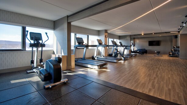 Un gimnasio moderno con cintas de correr, elípticas y equipos de levantamiento de pesas.