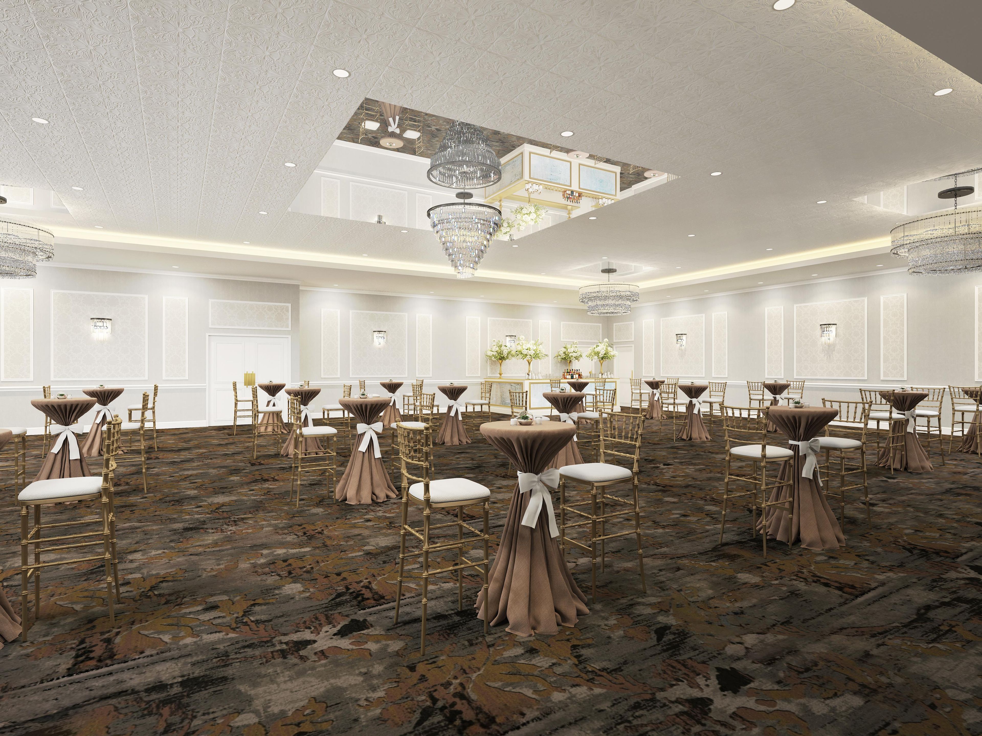 A spacious banquet hall with round tables, chairs, and a high ceiling with chandeliers.