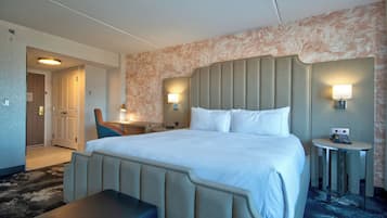 Une chambre d’hôtel avec un grand lit, un bureau, une chaise, une petite table et un banc.