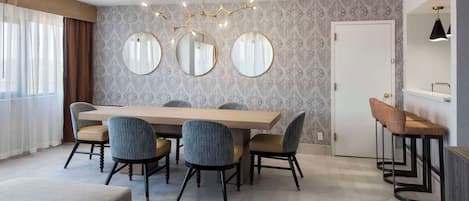Un'elegante zona pranzo moderna con un tavolo di legno e quattro sedie, un lampadario e un grande specchio a parete.