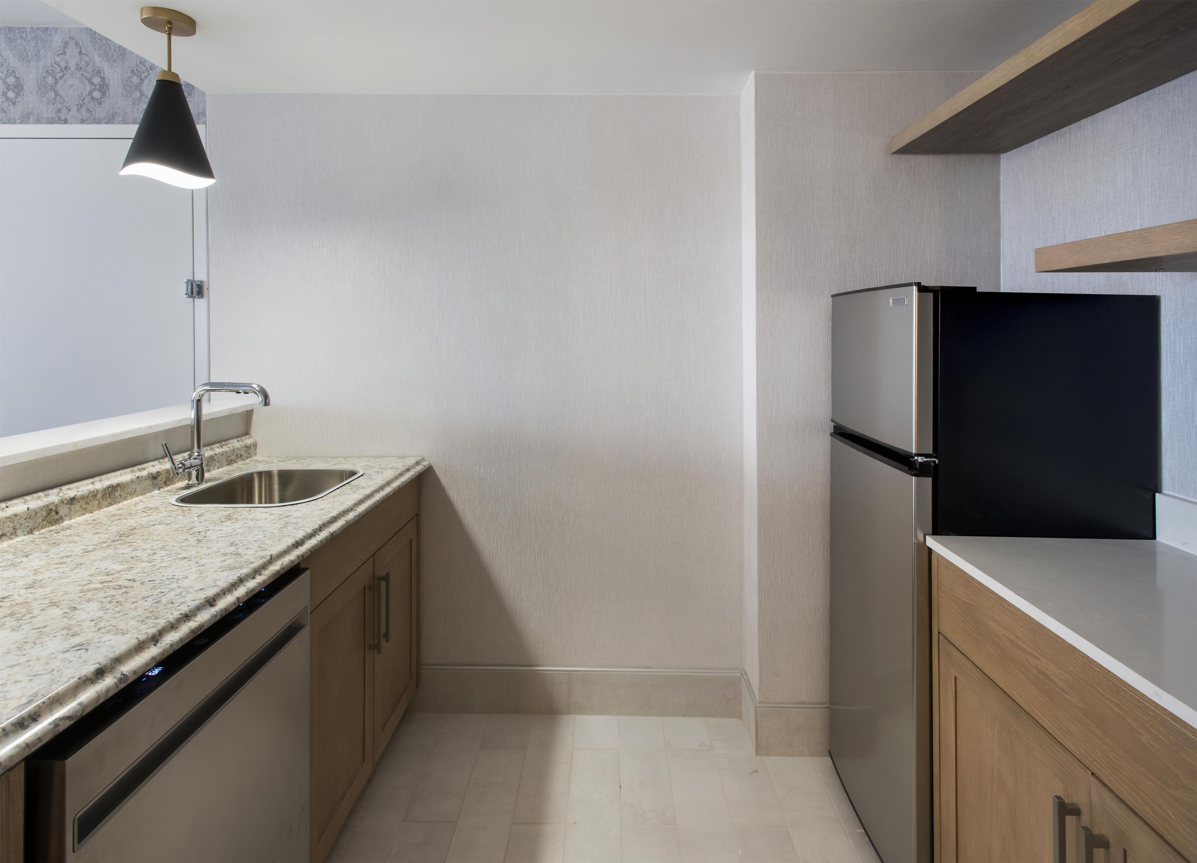 Cozinha moderna com bancada de granito, pia de aço inoxidável e refrigerador preto.