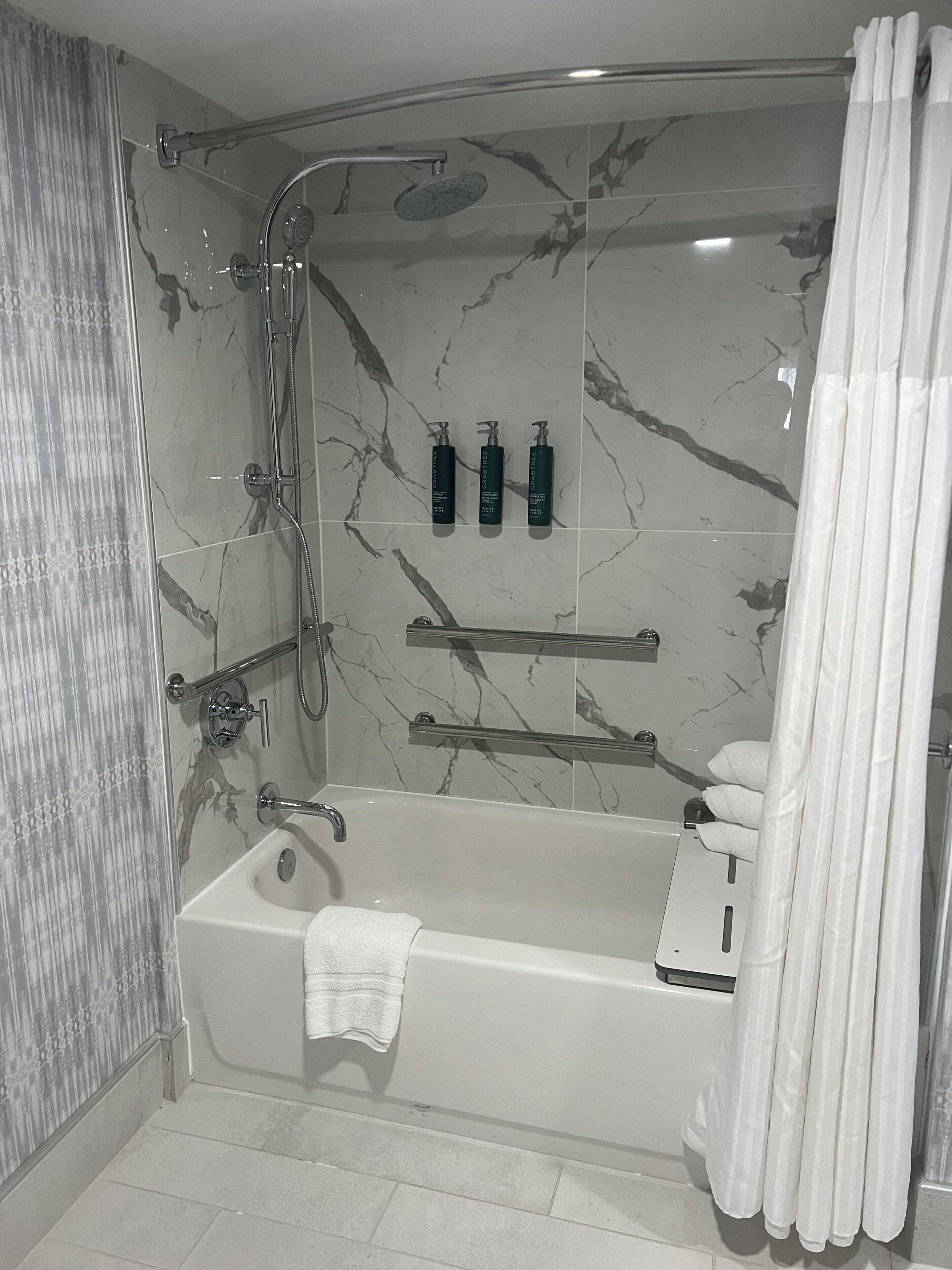 A modern bathroom with a glass-enclosed shower, a bathtub, and a vanity with toiletries.
