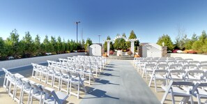 An outdoor wedding venue with rows of white chairs, a stone altar, and a clear sky. - DoubleTree by Hilton Poughkeepsie Convention Center (Poughkeepsie)