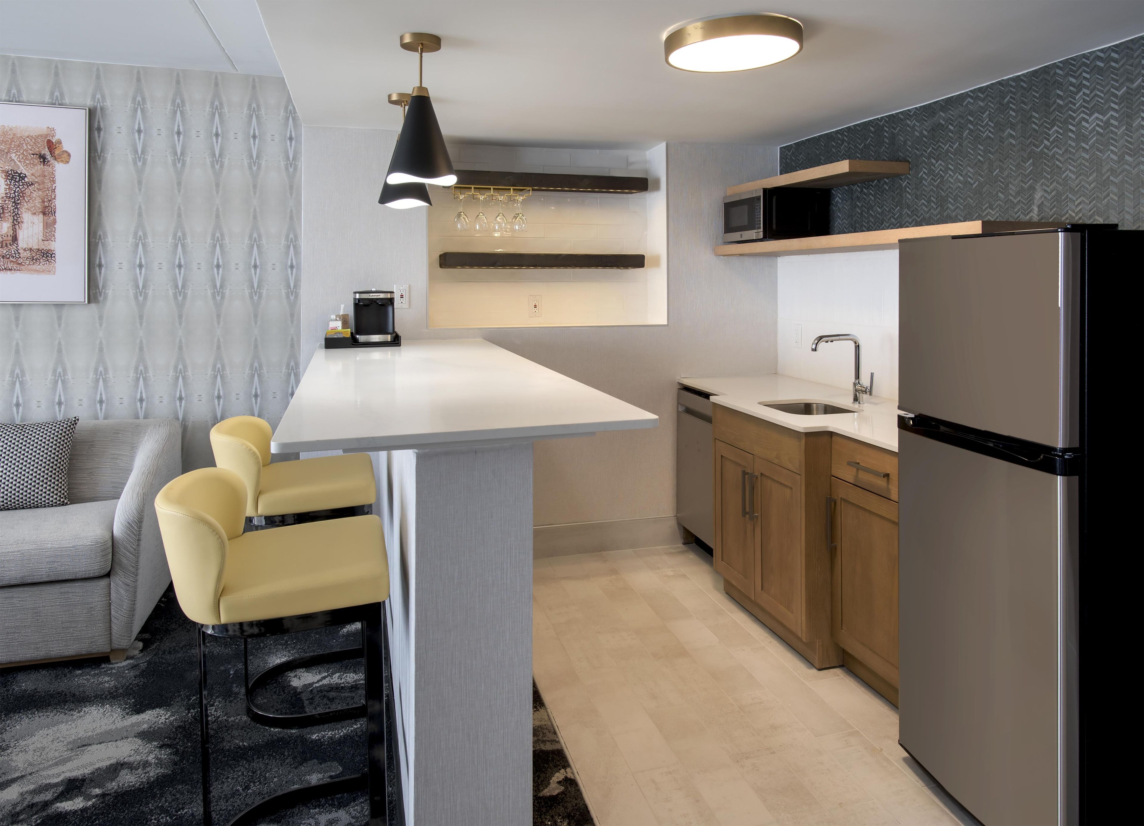 Una cocina moderna con una isla central, microondas empotrado y refrigerador de acero inoxidable.