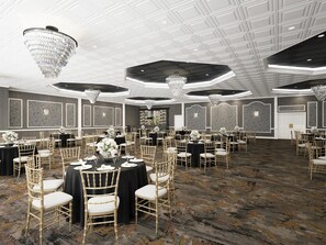 Une salle de banquet spacieuse, avec des tables rondes, des chaises dorées et des lustres.