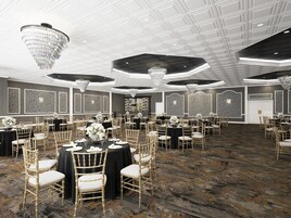 Un amplio salón de banquetes con mesas redondas, sillas doradas y candelabros.