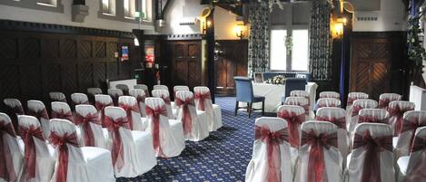 A church interior with rows of white chairs with red sashes, a blue patterned carpet, and wooden pews.