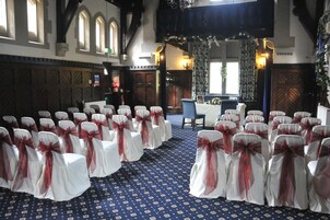 A church interior with rows of white chairs with red sashes, a blue patterned carpet, and wooden pews.