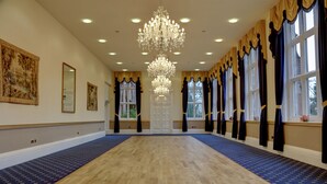 A spacious room with a large chandelier, wooden flooring, and patterned carpets. - Bestwood Lodge (Nottingham)