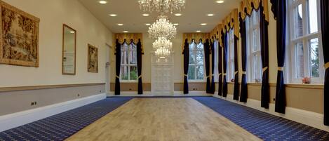 Une pièce spacieuse agrémentée d’un grand lustre, d’un parquet en bois et de tapis à motifs.
