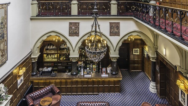 A grand interior with a high ceiling, ornate wooden paneling, and a central chandelier. - Bestwood Lodge (Nottingham)