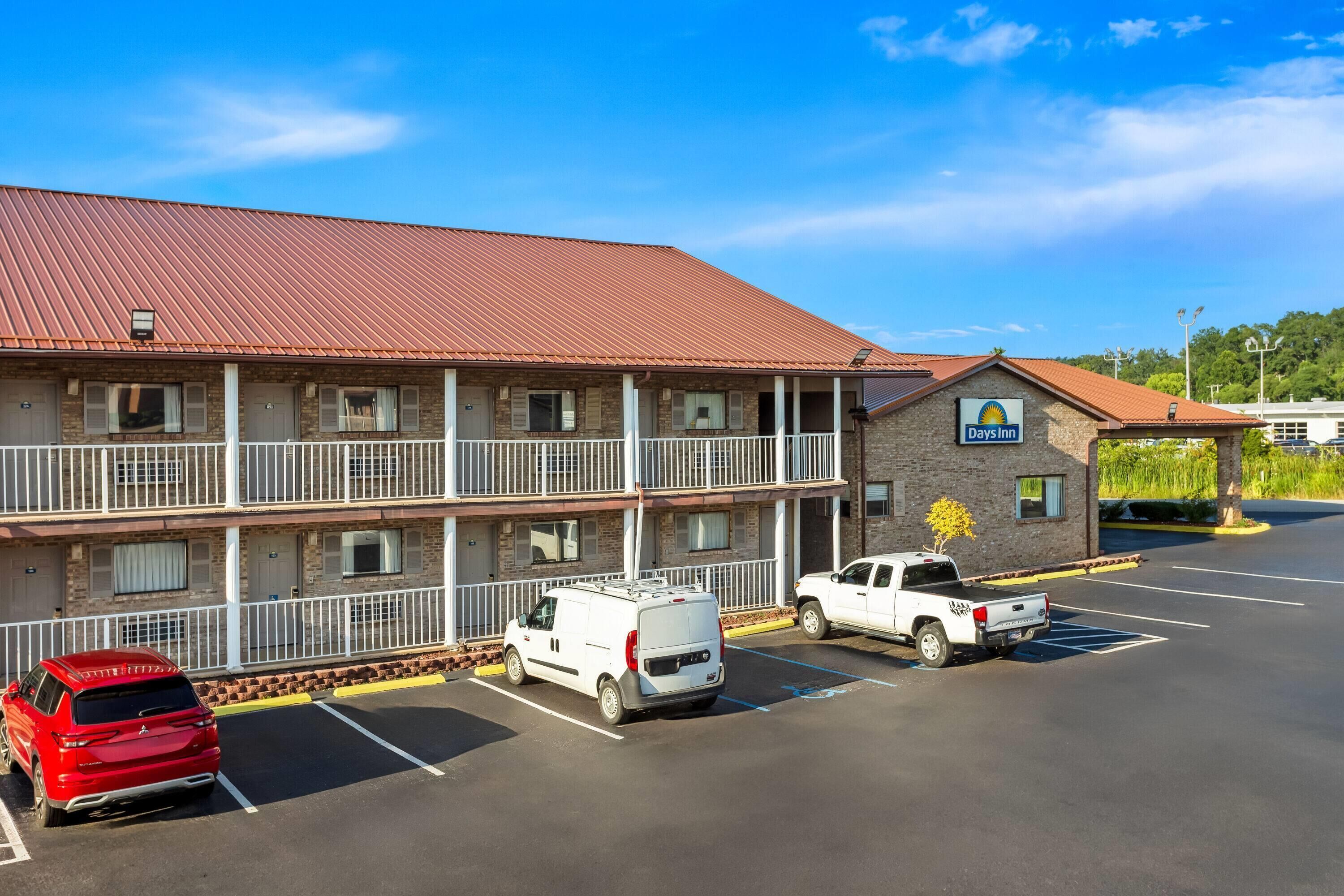 Un motel avec un toit rouge, une enseigne « Days Inn » et un parking où sont stationnés plusieurs véhicules.