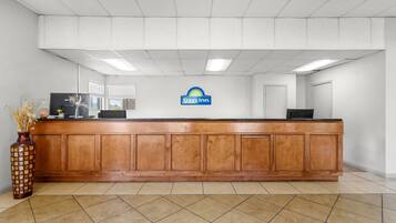A reception desk with a Days Inn sign, a wooden counter, and a vase with dried flowers.